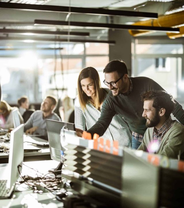 Group-of-happy-computer-programmers-working-together-on-desktop-PC-at-corporate-office-scaled